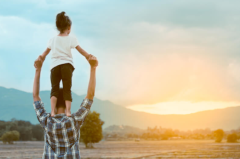 child standing on father's shoulders